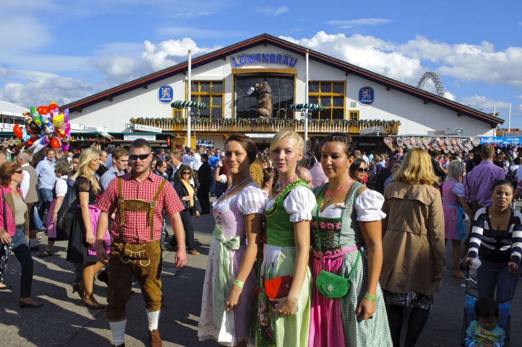 En gruppe mennesker i tyrolertøj samlet foranen stor ølhal - oktoberfest
