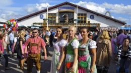 En gruppe mennesker i tyrolertøj samlet foranen stor ølhal - oktoberfest