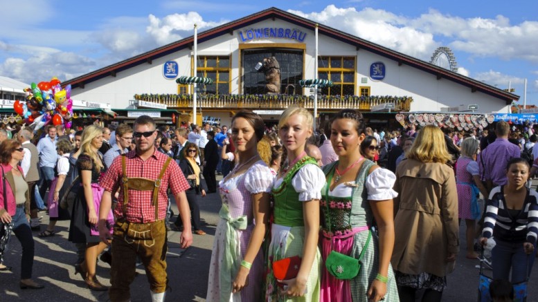 En gruppe mennesker i tyrolertøj samlet foranen stor ølhal - oktoberfest